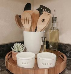 wooden utensils and spoons are arranged on a tray in front of a bottle