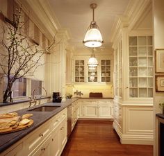 a kitchen with white cabinets and wood flooring next to a vase filled with flowers