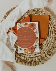 an orange and white baby shower is on top of a wicker basket next to some folded towels