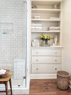 a white bathroom with open shelving and wooden flooring