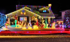 a house covered in christmas lights at night with lots of holiday decorations on the front