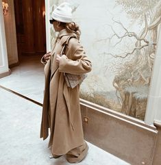 a woman standing in front of a wall with a painting on it's side