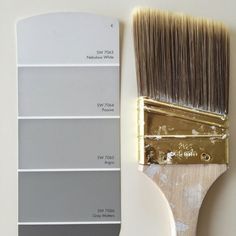 a paintbrush with some different shades of gray on it next to a white wall