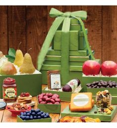 an assortment of fruits and cheeses on a wooden table with a green tower in the background