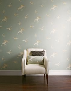 a chair sitting in front of a wall with birds on it