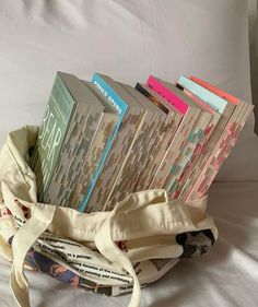 a bag filled with books sitting on top of a bed