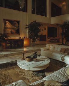 a living room filled with white couches next to a table and potted plants