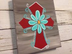 a cross painted on top of a wooden board with blue and red flowers in the center