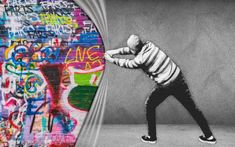 a black and white photo of a man in front of a graffiti wall