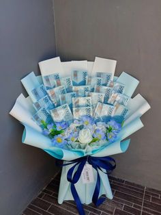 a bouquet of flowers is wrapped in blue and white paper with stamps on it, sitting against a gray wall