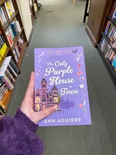 a person holding up a purple book in a library