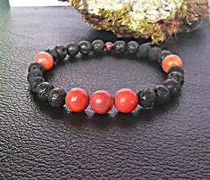 Introducing our stunning Black Lava Stone Bracelet with Red Jasper Gemstones. This captivating handmade crystal bracelet is not only adjustable but also showcases the perfect blend of style and versatility.  The contrasting colors create a bold and eye-catching design that is sure to impress. Whether you're looking for a red jasper bracelet for yourself or a thoughtful gift for your loved ones, this black lava bracelet fits the bill. It's suitable for both men and women, making it a versatile ac Black Lava Stone Bracelet With Gemstone Beads, Hand-strung Lava Stone Bracelets For Gift, Casual Hand-strung Beaded Bracelets With Lava Stone, Red Jasper Bracelet, Hand-strung Lava Stone Bracelets, Hand-strung Lava Stone Bracelets With Round Beads, Lava Stone Bracelet, Lava Bracelet, Jasper Bracelet