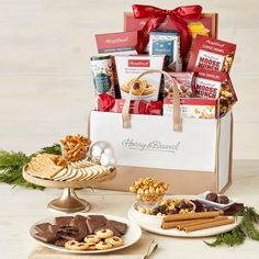 a gift bag filled with snacks and crackers next to two plates full of cookies