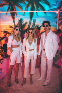 three people in white outfits standing next to each other on the beach with palm trees behind them