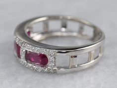 This ruby and diamond band has a bold geometry! The richness of the raspberry colored rubies pops against the bright shine of the white gold and diamond accents. This would make a special wedding or anniversary band, but would also look great as a stacking ring! Metal: 14K White Gold Gem: 3 Rubies; 40 Diamonds totaling .18 Carats, SI in Clarity, G in Color Width of Band: 6 mm Height off Finger: 3.1 mm Ring Size: 5.75 Marks: "14K" Stamped on the inside band Luxury White Gold Ruby Ring With Brilliant Cut, Anniversary White Ruby Ring With Multi-stone, Gift Ruby Ring In White Gold With Multi-stone, Silver-colored Platinum Ruby Ring For Anniversary, Luxury Hallmarked White Gold Ruby Ring, Ruby Bands, Star Ruby, Ruby Diamond, Ring Metal