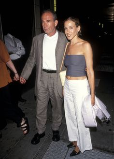 a man and woman walking down the street at night, one wearing a strapless top