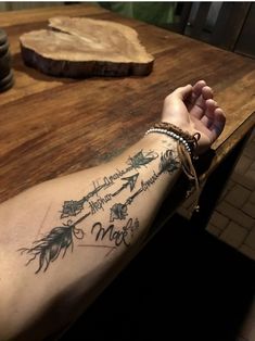 a person with a tattoo on their arm holding onto a piece of wood next to a knife