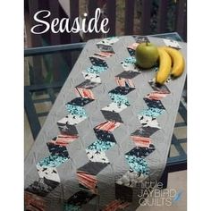 a quilted table with two bananas on it and the words seaside written in white