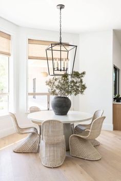 a dining room table with four chairs and a vase on the centerpiece in front of it