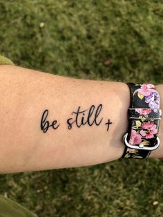 a woman's arm with a tattoo saying be still and flowers on the wrist