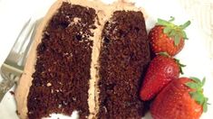 a piece of chocolate cake and two strawberries on a plate