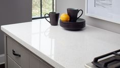 a kitchen counter with two cups and plates on it, one has an orange in the middle