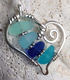 three sea glass pieces in a heart shaped pendant