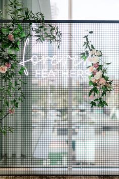 flowers and greenery are hanging on the glass wall