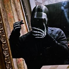 a man wearing a skeleton mask is taking a selfie in front of a mirror