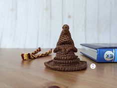 a crocheted christmas tree sitting on top of a wooden table next to a book