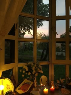 a table with flowers and candles on it in front of a window that is lit up