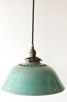 a green light hanging from a ceiling fixture with a black cord attached to the end