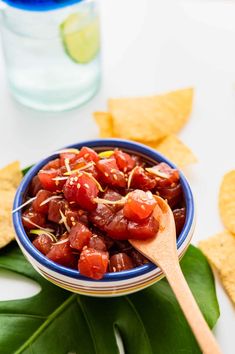 a blue bowl filled with salsa and tortilla chips on top of a white table