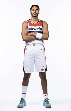 a man standing with his arms crossed in front of him, wearing a basketball uniform