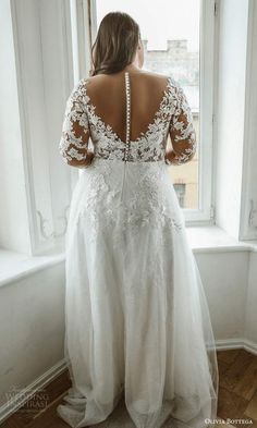 a woman in a wedding dress looking out the window