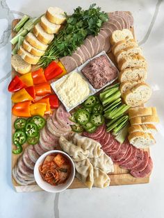 a wooden cutting board topped with meats and veggies