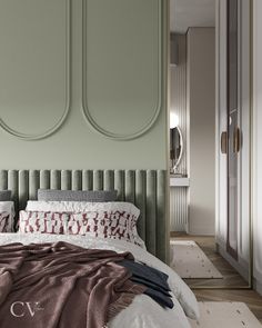 a bed with pillows and blankets on top of it in front of a green wall