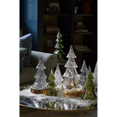 glass christmas trees sitting on top of a table in front of a book shelf and couch