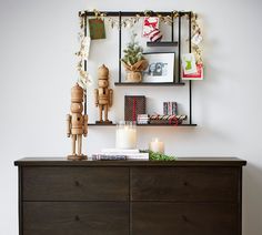 a wooden dresser topped with lots of books and candles next to a wall mounted shelf