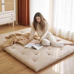 a woman sitting on the floor reading a book