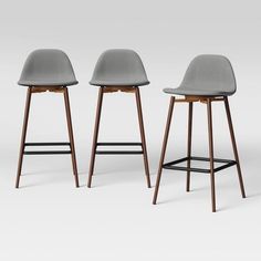 three modern stools with wooden legs and grey upholstered seat, all in different colors