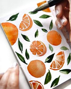 someone is painting oranges on a piece of paper