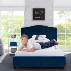 a young boy laying on top of a bed