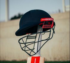 a baseball helmet on top of a wooden base with a red and white stripe around it