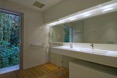 a bathroom with a large mirror, sink and walk in shower next to a sliding glass door