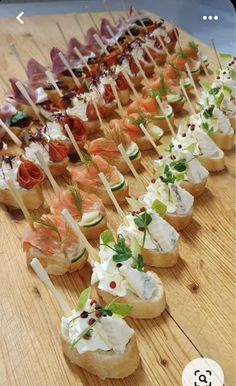 a wooden table topped with lots of appetizers on skewered breads