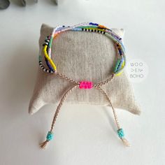 a white pillow sitting on top of a table next to a bracelet with beads and tassels