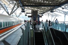 an escalator with people walking up and down it in a train station,