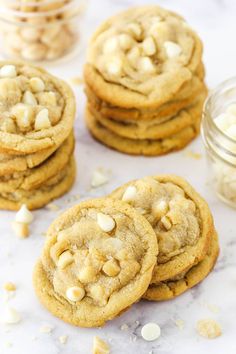 white chocolate chip cookies are stacked on top of each other, with more cookies in the background