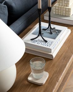 a table with a book, candle holder and glass on it next to a couch